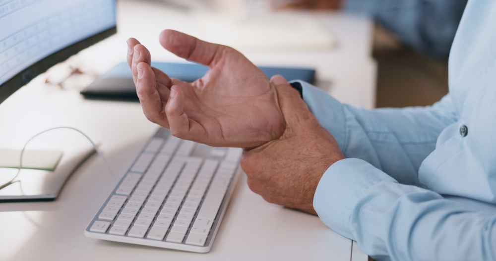 Person holding their wrist due to numbness and tingling associated with carpal tunnel syndrome.